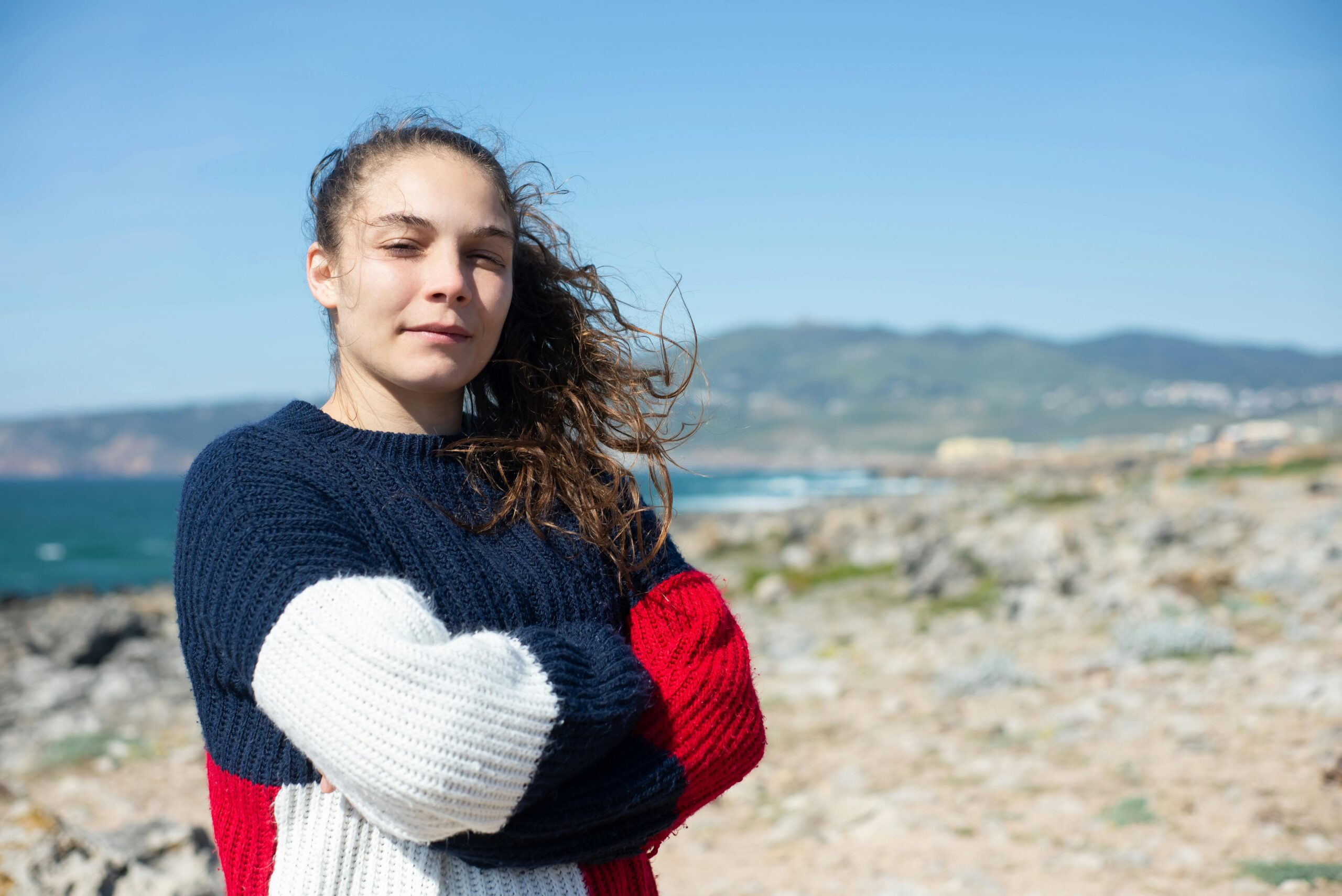 Woman stands confidently by scenic rocky Portugal coast.
